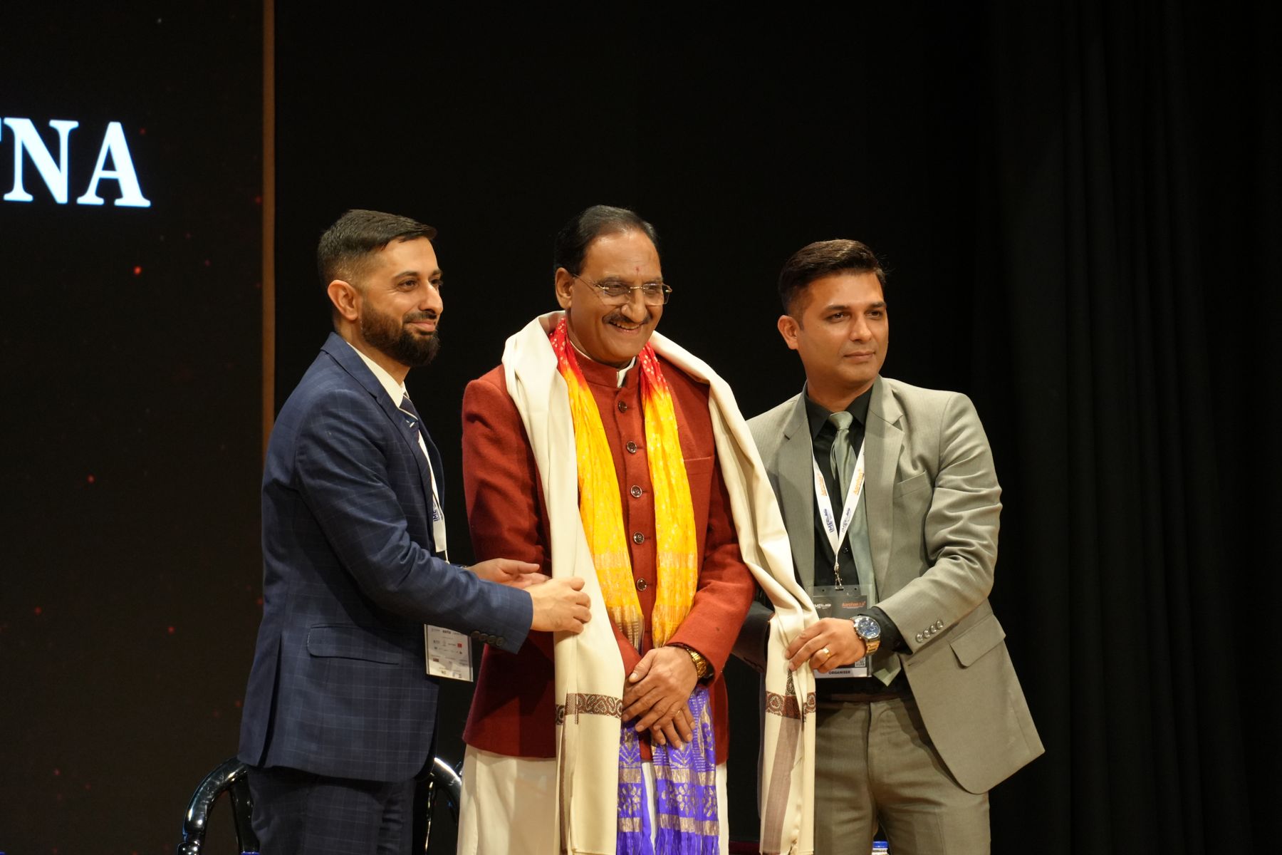A guest being felicitated with a shawl on stage