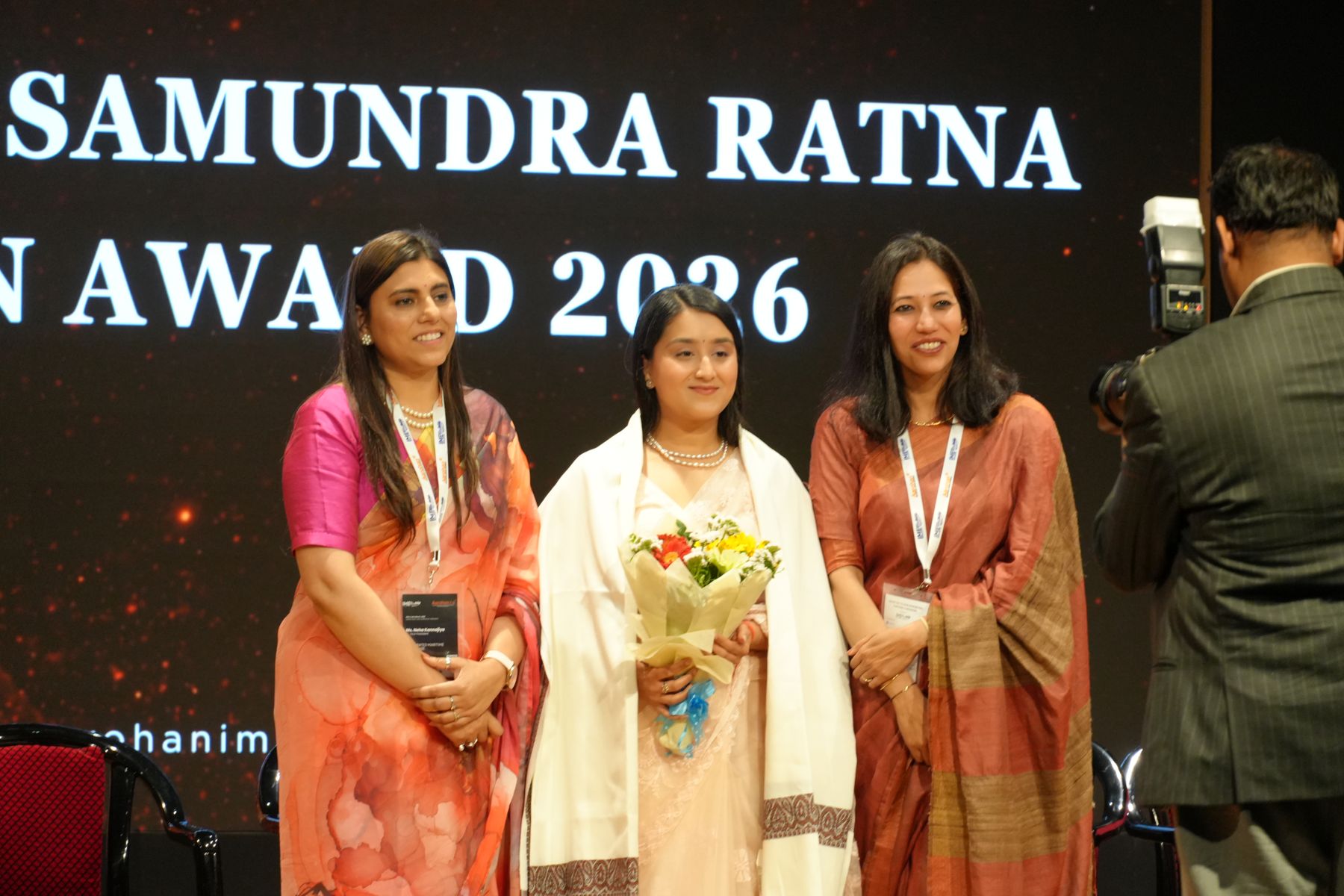 Award recipients posing on stage with a bouquet