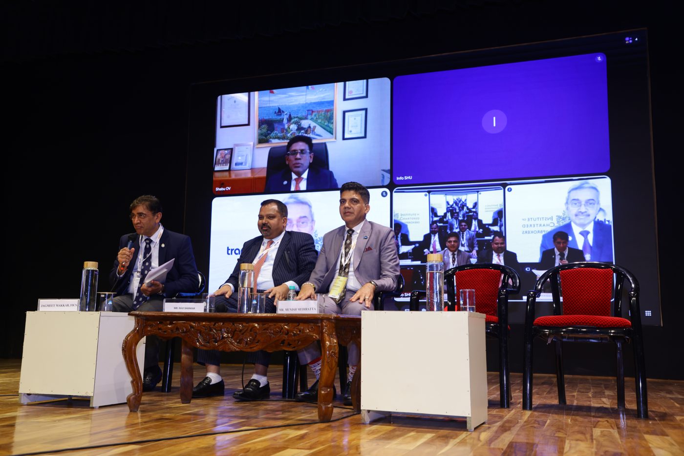 Speakers on stage with remote panellists joining online on the conference screen